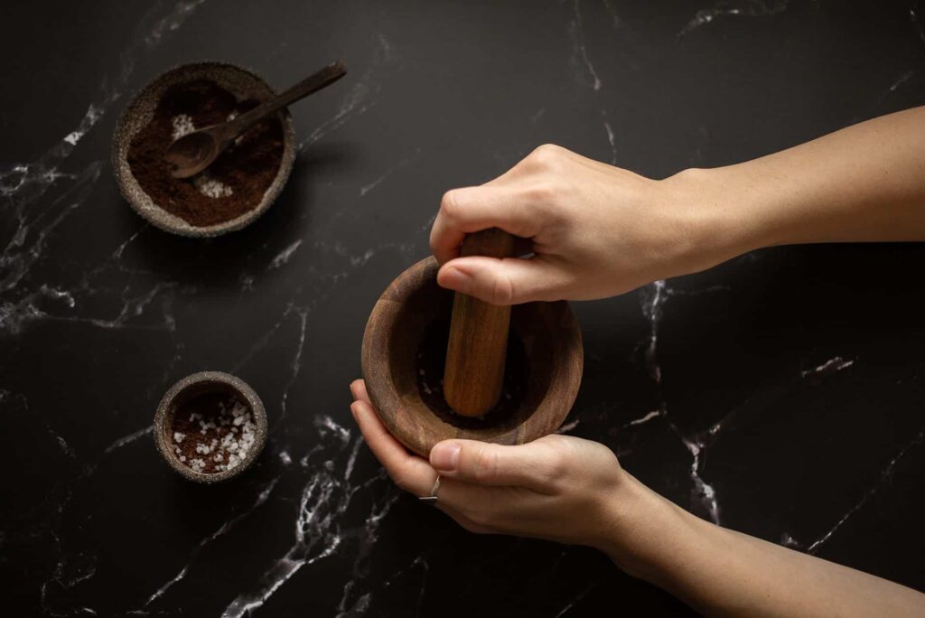black marble tabletop with mortar and pestle, salt and herbs.